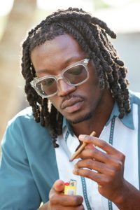 First-time smoker holding a cigarillo and lighter with a curious smile