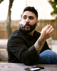 Man lighting a cigarillo outdoors during sunset