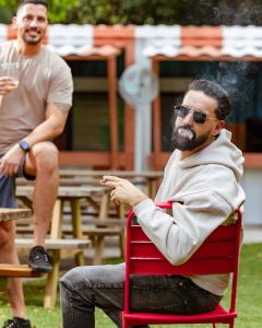 A group of friends sharing cigars and drinks on the patio at night