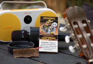 Al Capone limited edition promotional natural leaf wraps and some instruments on a wooden outdoor table in summer sunlight