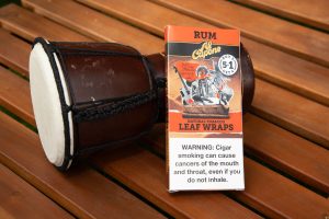 Al Capone limited edition promotional natural leaf wraps and some instruments on a wooden outdoor table in summer sunlight