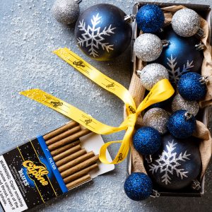Holiday gift bags filled with wine, chocolates, candles, and Al Capone cigarillos on a festive table