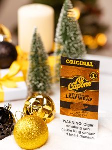 Holiday gift bags filled with wine, chocolates, candles, and Al Capone cigarillos on a festive table