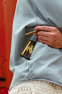 Cozy cabin scene with luggage, blankets, snacks, firewood, and Al Capone cigarillos on a rustic table