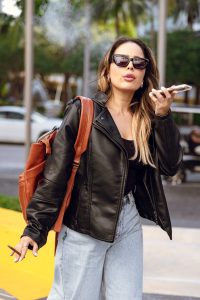 Scenic weekend getaway with packed bags, cozy cabin view, wine glasses, and Al Capone cigarillos placed for adult relaxation