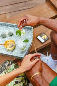 A cigar resting beside a classic cocktail on a bar