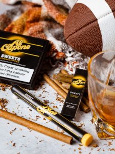 Thanksgiving weekend table with dinner spread, football on in the background, and Al Capone cigarillos for the after-dinner tradition